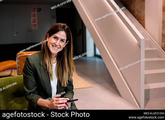 Happy businesswoman with smart phone at office