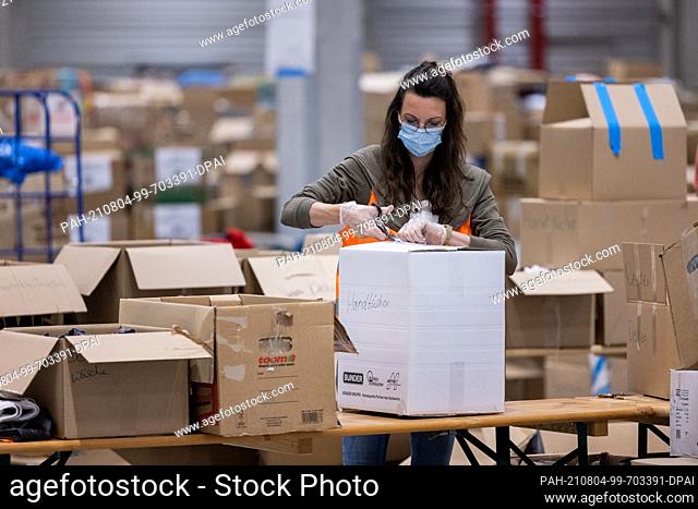 04 August 2021, North Rhine-Westphalia, Zülpich: A woman sorts donations in kind for the victims of the flood disaster in a logistics warehouse of the German...