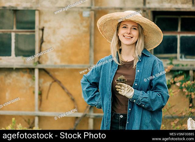 Smiling woman holding vegetable seedling in garden