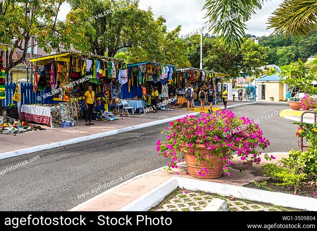 Ocho Rios, Jamaica - April 22, 2019: Souvenir street market in the tropical Caribbean island of Ocho Rios, Jamaica. Flowerbed in the foreground
