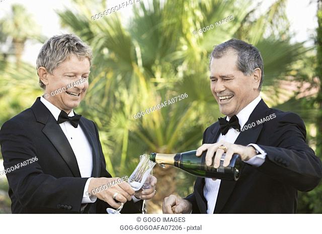 Newlywed gay couple pouring themselves champagne