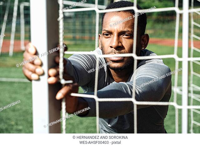 Portrait of sportsman stretching exercise behind net