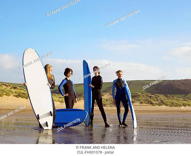 Four female surfers standing on a beach