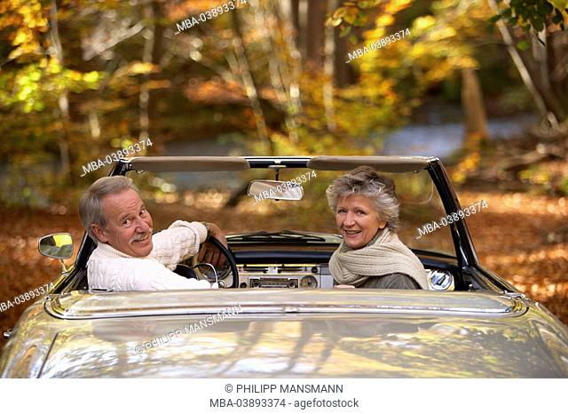 Forest, car, senior couple, Cabrio, stern-opinion, gaze shoulder, cheerfully, autumn, pension, couple, people, 66 years, 60-70 years, seniors, two, pair, ages