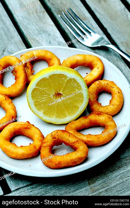 Fried calamari rings with lemon in white plate