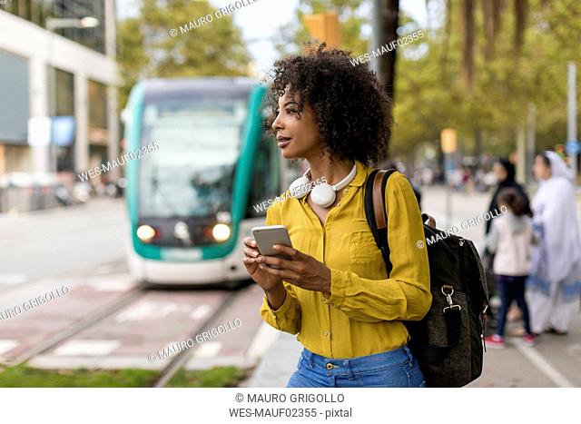 Woman with backpack and headphones using smartphone in the city