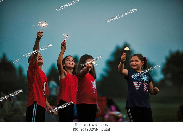 Group of friends, arms raised holding sparklers