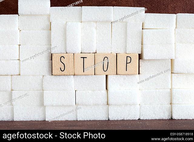 Pile or wall of sugar cubes and stop word in block letters as advise on addiction calories excess and sweet unhealthy food abuse causing health problem and...