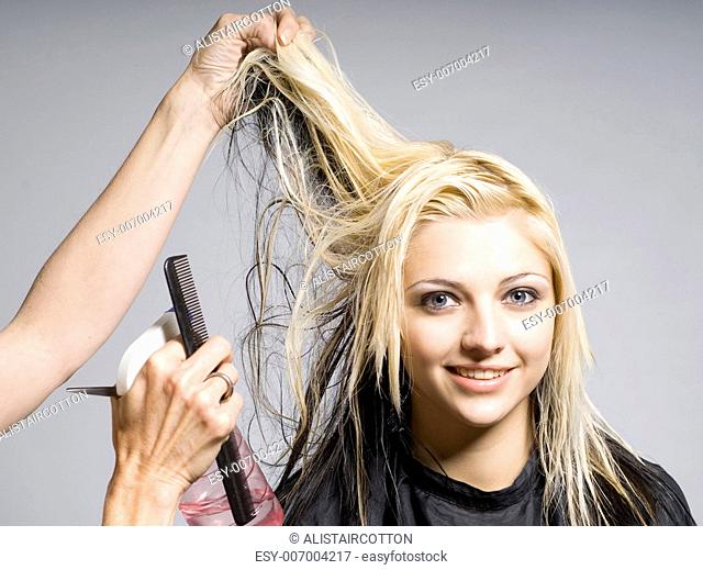 Hairdresser cutting hair of woman of smiling girl