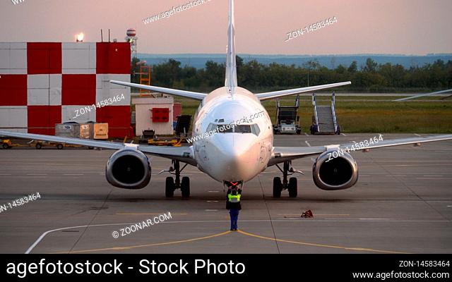 KAZAN, RUSSIAN FEDERATION - JENE 17, 2019: Marshal controls the parking of the aircraft after the arrival and taxiing