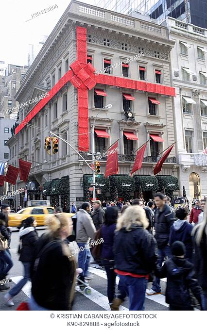 Pedestrians on Fifth Avenue, passing by the building with the Cartier jewellery shop which has been decorated and wrapped as present during the Christmas...
