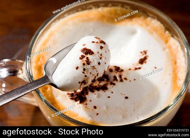 photo of cappuccino in glass cup on wood table