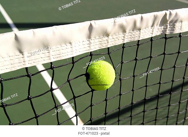 A tennis ball stuck in a tennis net