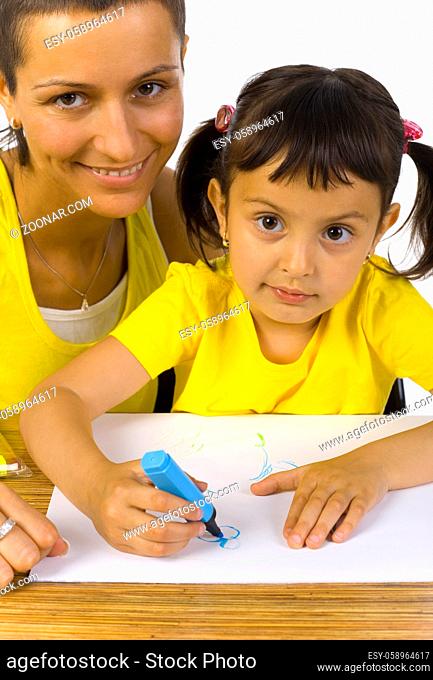 Smiling mother sitting with daughter at desk. Writing something with blue marker. Looking at camera, white background
