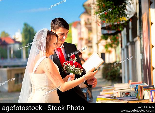 Bride and groom. Portrait of a loving wedding couple reviewing vintage books in antique book shop in medieval city center of Ljubljana, Slovenia
