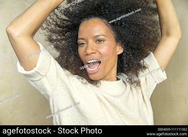 Close up portrait of a mixed race middle aged woman singing with her hands up in the air