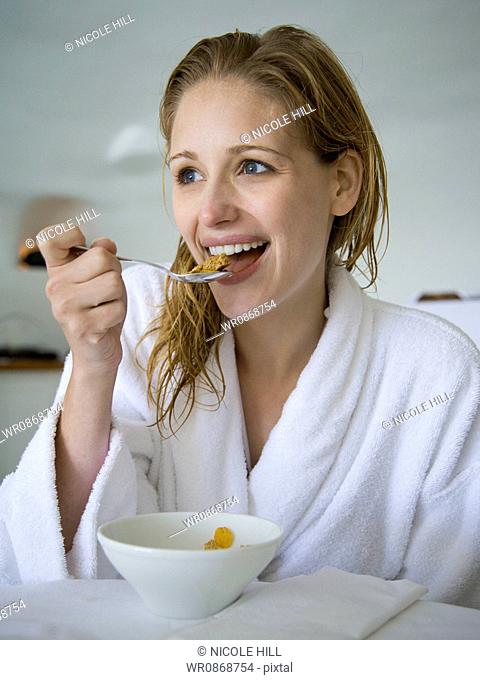 Woman in bathrobe eating cereal