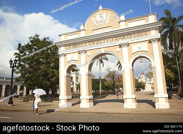 Cuban woman with an umbrella in front of the Arch Of Triumph-Arco Del Triunfo at Parque Jose Marti in Plaza de Armas Square, Cienfuegos, Cuba, West Indies