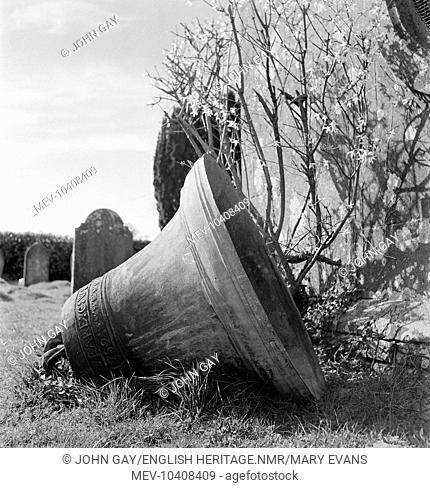 A church bell lying on its side in the churchyard of St Osmond's Church in Melbury Osmond, bearing the inscription Charles Weare C. W. 1752