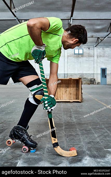 Mature male athlete practicing roller hockey while aiming at wooden box