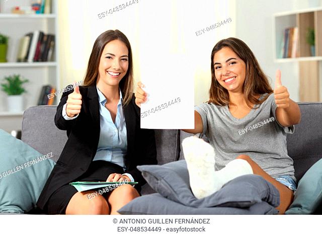 Happy insurance agent and disabled client showing contract with thumbs up at home