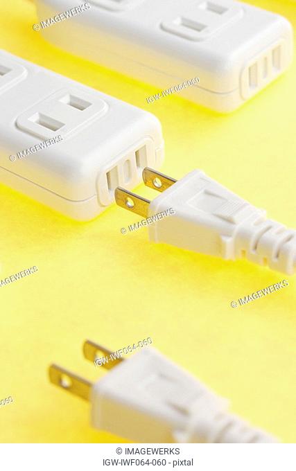 Extension cords and extension sockets on yellow background, close-up