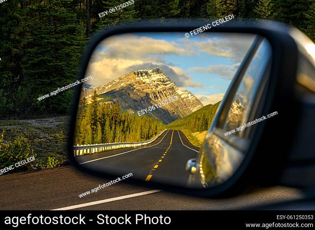 Driving a car through a mountain road that leads through the Canadian Rockies and watching the beautiful scenery in the rearview mirror in the icefields parkway