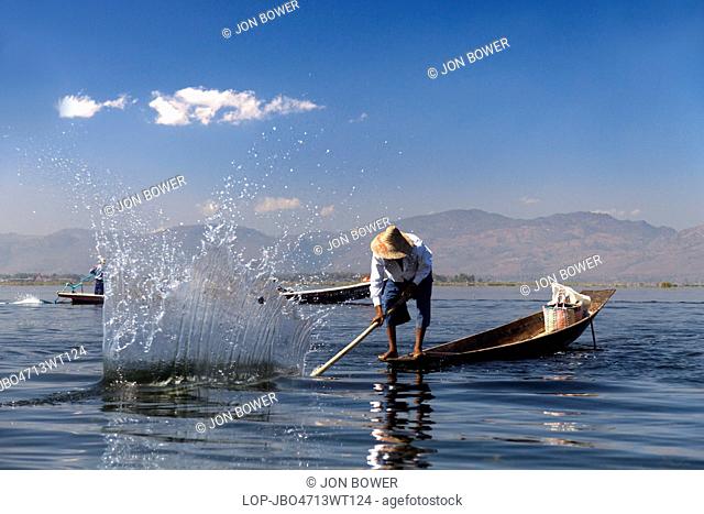 Myanmar, Shan, Lake Inle. Fisherman beating the water to attract fish on Lake Inle in Myanmar