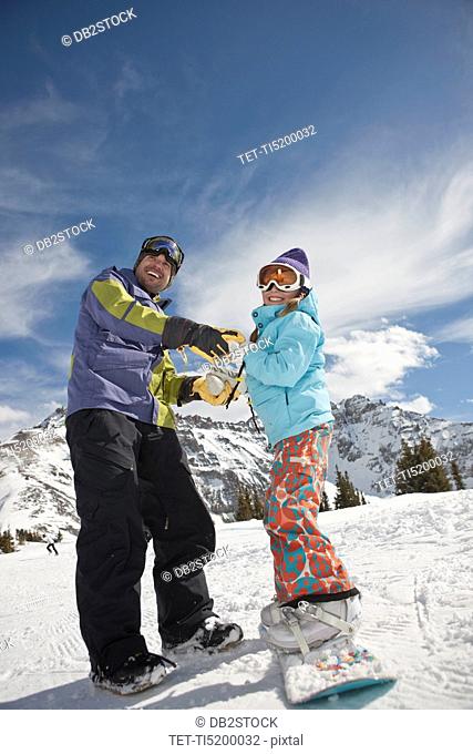 USA, Colorado, Telluride, Father helping daughter 10-11 with snowboard binding