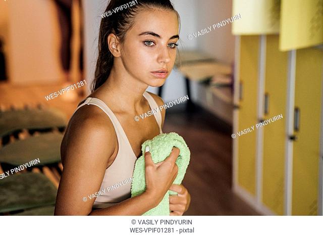 Young woman in locker room finishing workout in gym