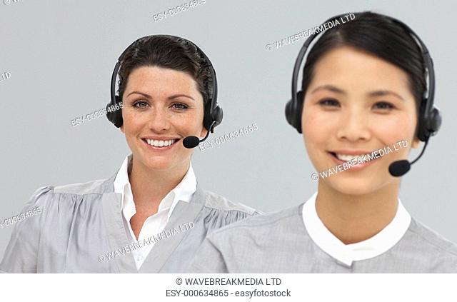 Smiling young businesswomen with headset on looking at the camera