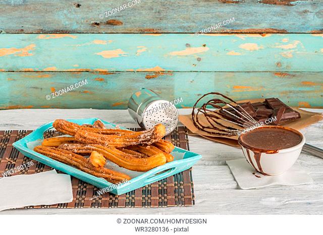 Traditional churros with hot chocolate dipping sauce on wooden counter top