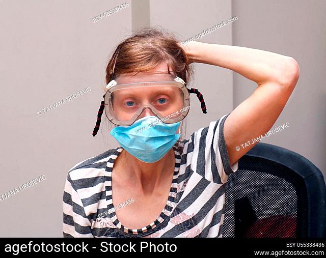 Young woman with face and eye masks on her face as virus protection inside interior