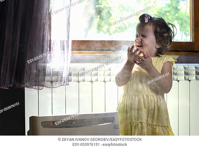 Little girl in a dusty room. Air purifier and coughing kid. Dust in the air. Allergy concept