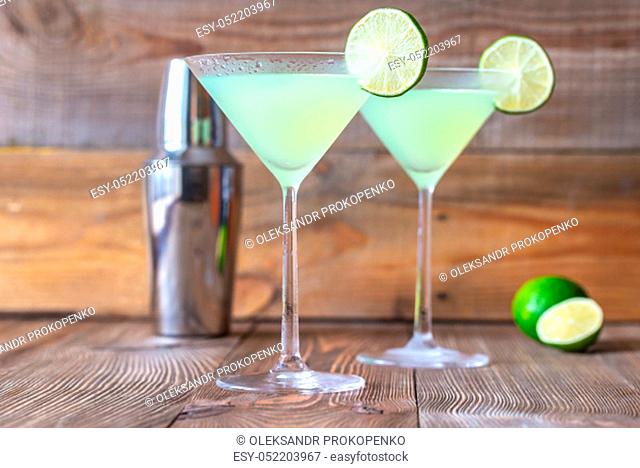 Two cocktail glasses of classic daiquiri on the wooden background