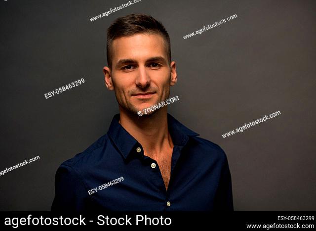 Man in black shirt looking t camera and smiling isolated on grey background. Fashion or vogue concept. Picture of handsome model man posing in studio for...