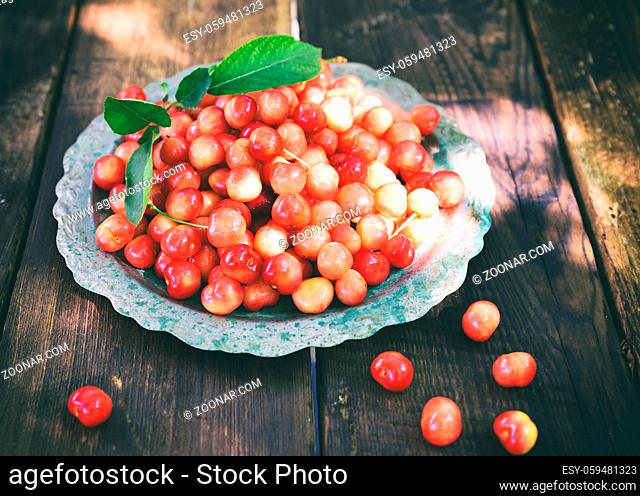 Ripe red cherry in an iron plate, top view