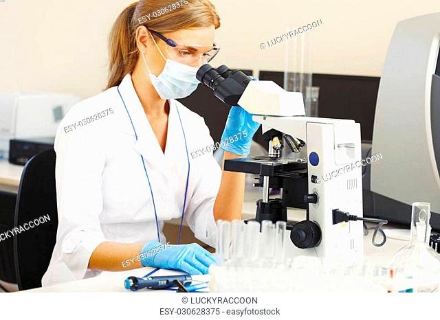 Beautiful woman in a laboratory working with a microscope