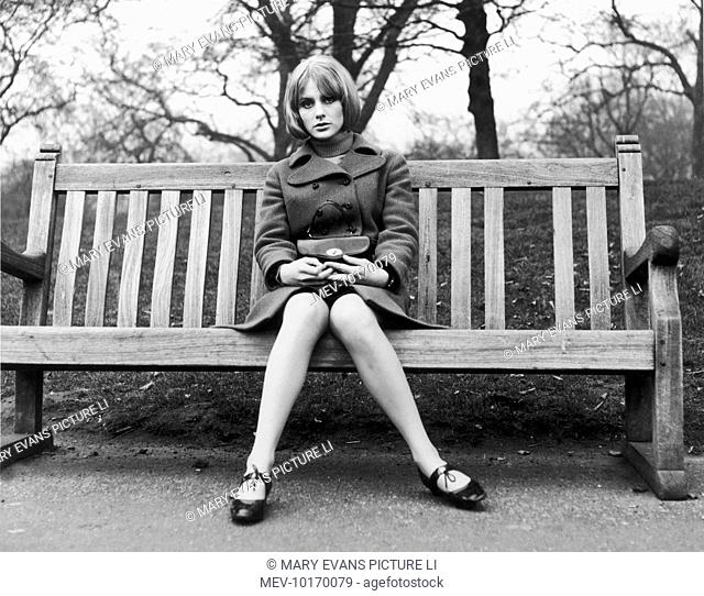 A woman sits on her own on a park bench
