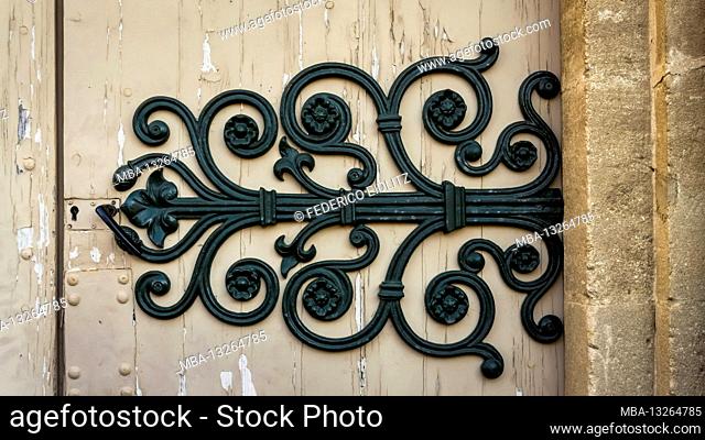 Iron fittings on the entrance door of the single-nave church of Saint Etienne. It was built in the Languedoc Gothic style between the XIII and XVII centuries in...