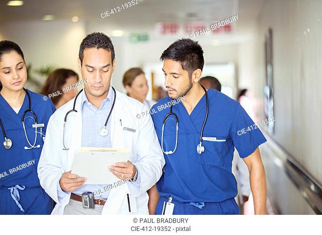 Doctor and nurses reading medical chart in hospital hallway