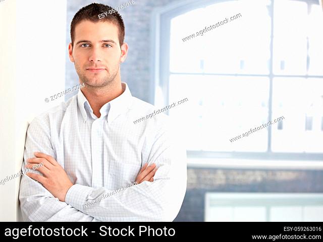 Goodlooking young man standing arms crossed