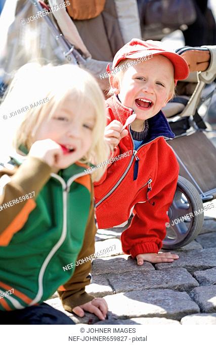 Two boys eating a lollipop