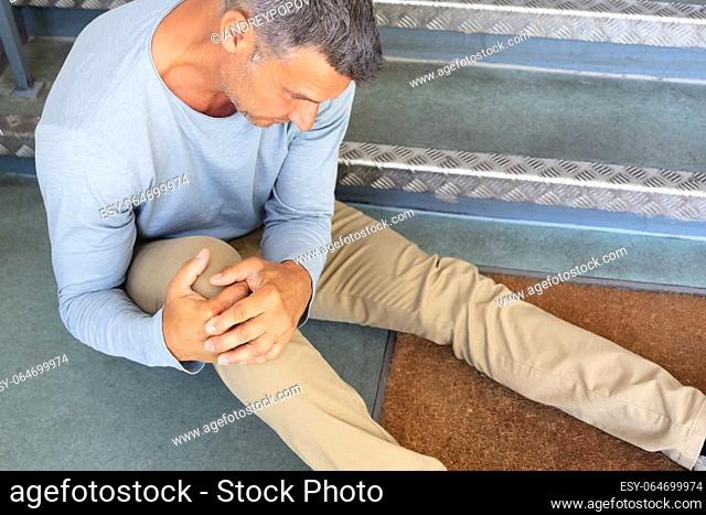 Mature Man Sitting On Staircase After Slip And Fall Accident
