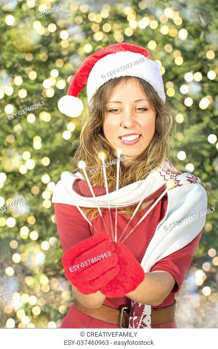 Beautiful Santa Claus girl with Christmas sparklers outdoors