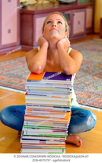 Eine Studentin sitzt vor einem Stapel Bücher beim lernen