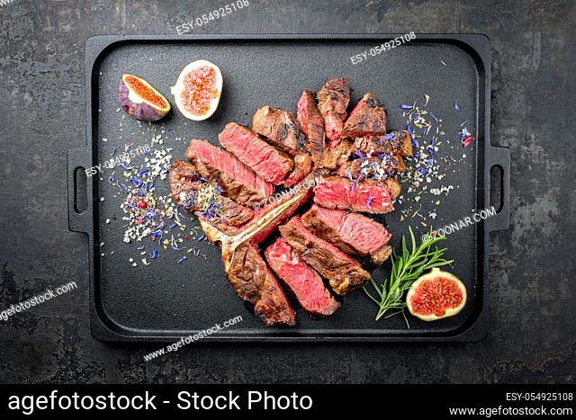 Traditional barbecue dry aged wagyu porterhouse steak sliced with fruit and spice as top view on a modern design tray