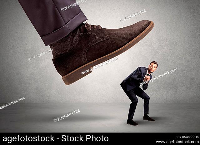 Employee is afraid of the big boss foot, which is stepping down him