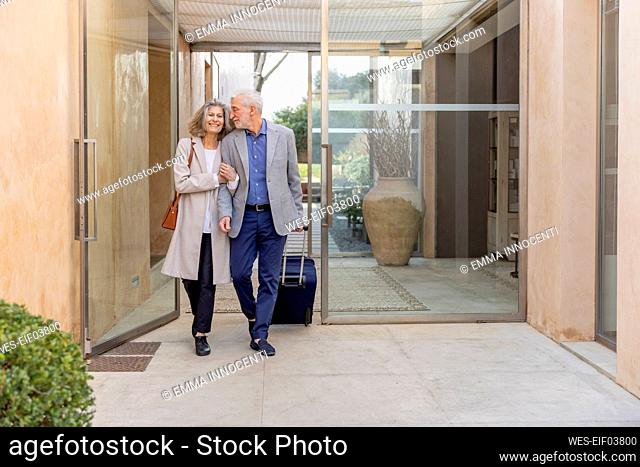 Smiling senior couple walking in lobby at boutique hotel