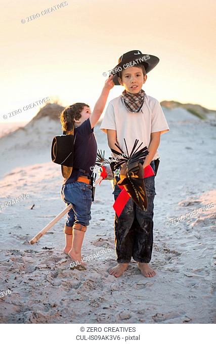 Two brothers dressed as cowboy's reaching for hat